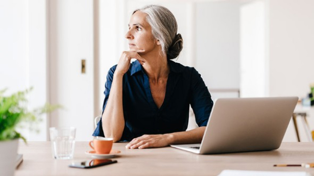 femme qui pense pendant son télétravaille avec la tête en direction de la fenêtre