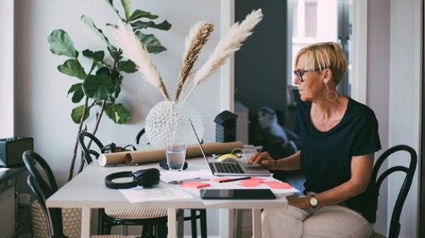 Femme qui travaille sur une table à manger chez elle